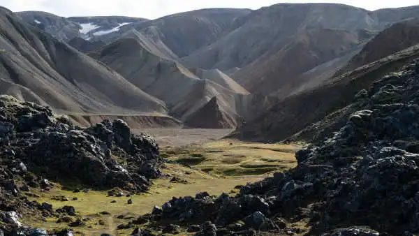 Dark obsidian lava field and brown-orange mountains